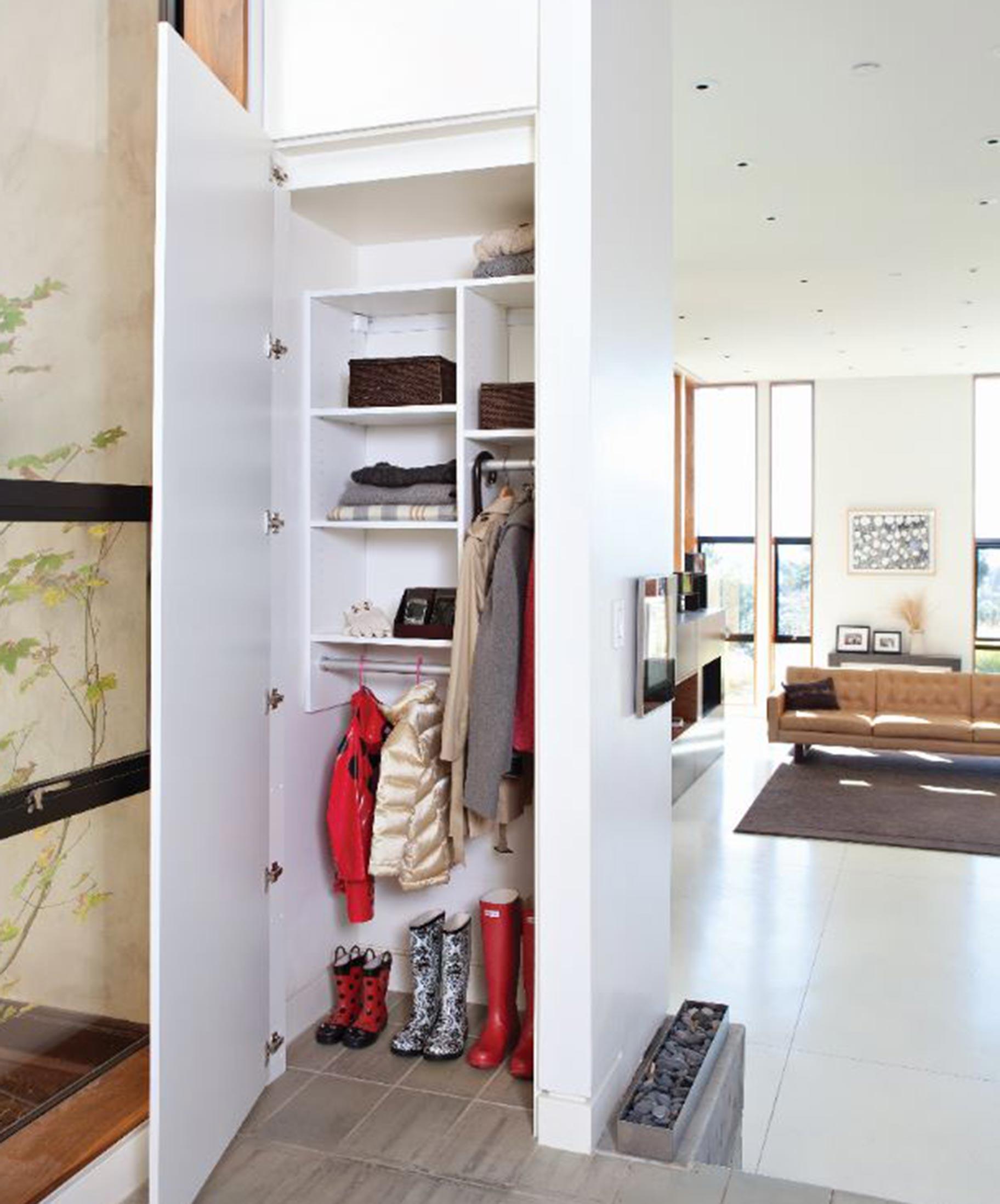 Small closet view from hallway with custom shelving and hanging poles for organization by California Closets