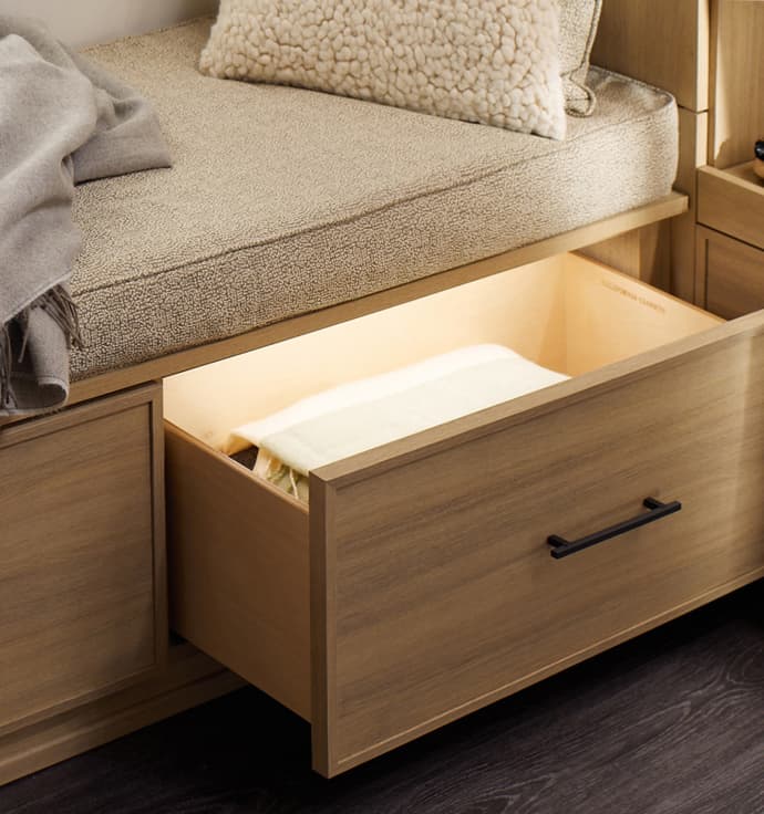 Custom bench with storage drawers lit up with LED lighting in light wood grain finish by California Closets