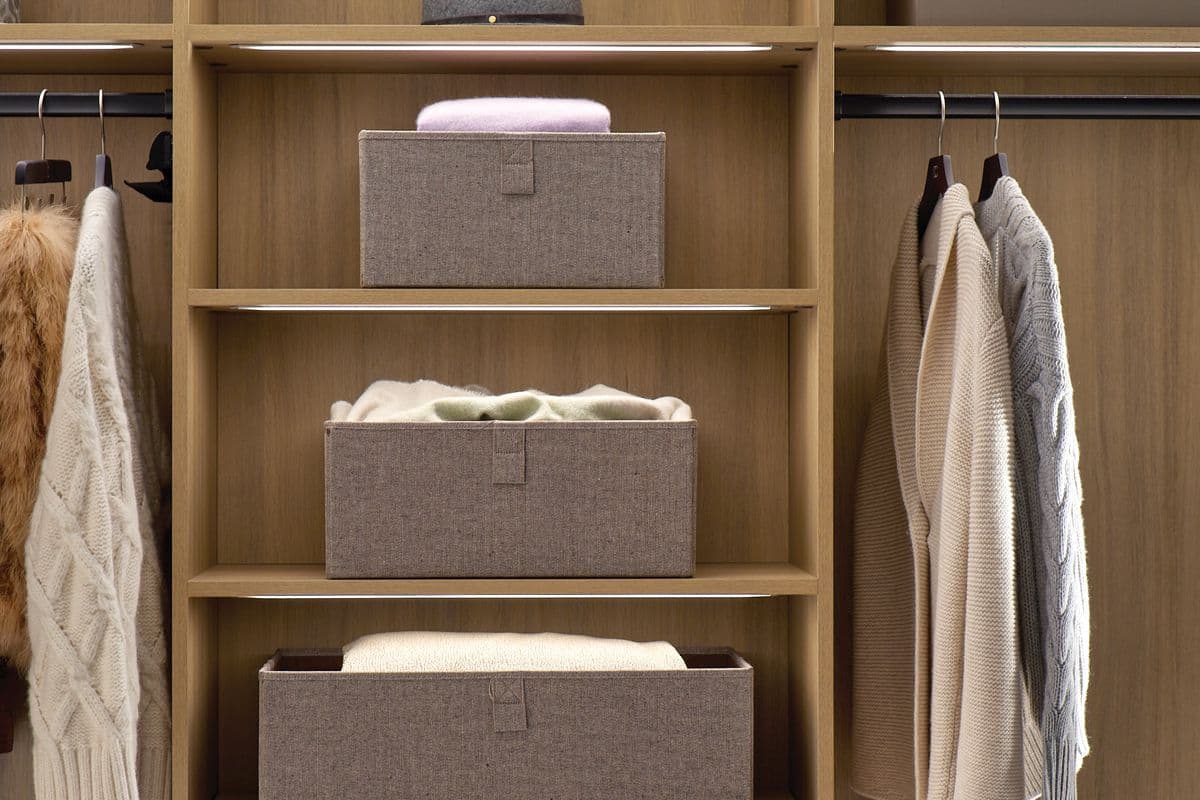 Armario con estantes abiertos y barras para ropa con iluminación LED en acabado de veta de madera natural de California Closets