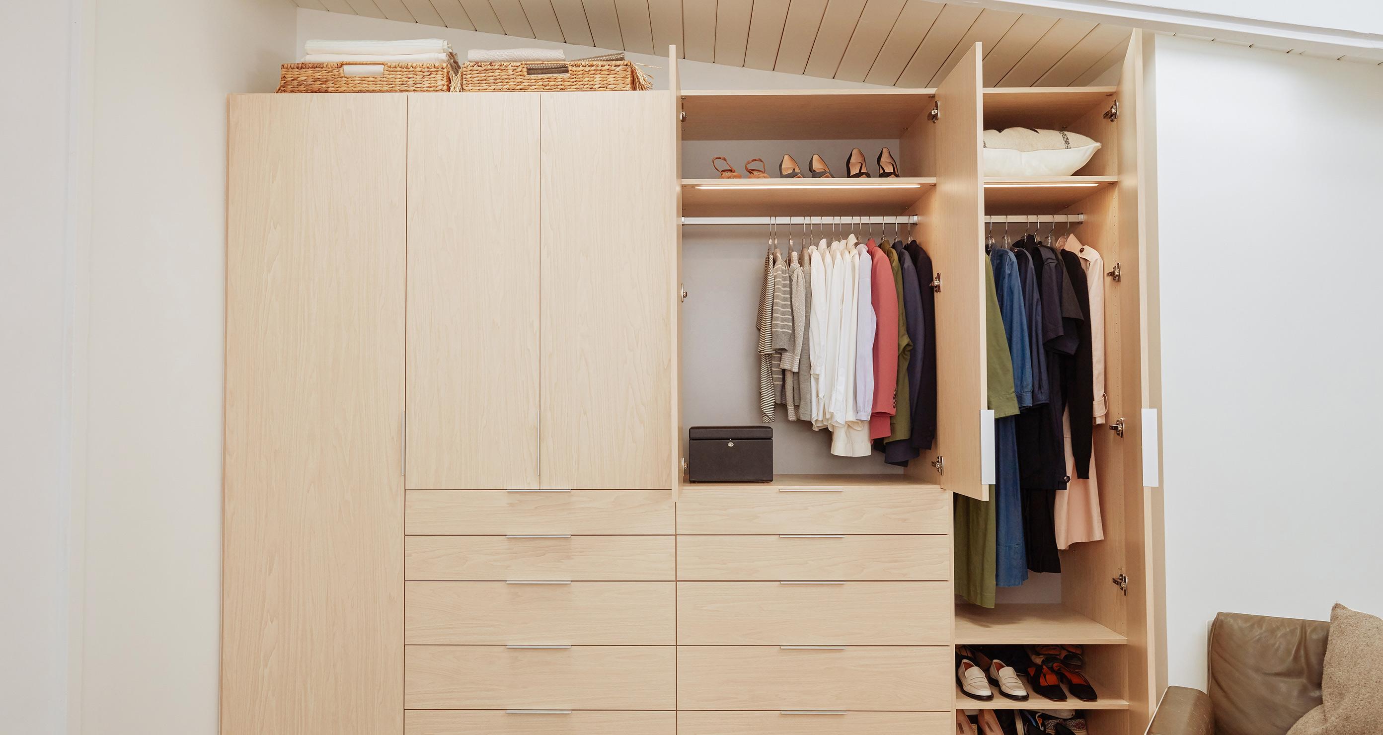 Acceda al armario diseñado debajo de las escaleras con gabinetes de madera natural de California Closets