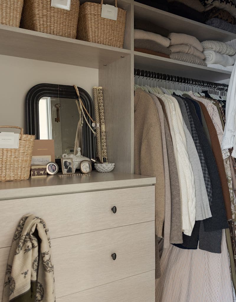 Armario vestidor con estanterías, cómoda empotrada y barras para colgar la ropa en acabado de madera clara de California Closets