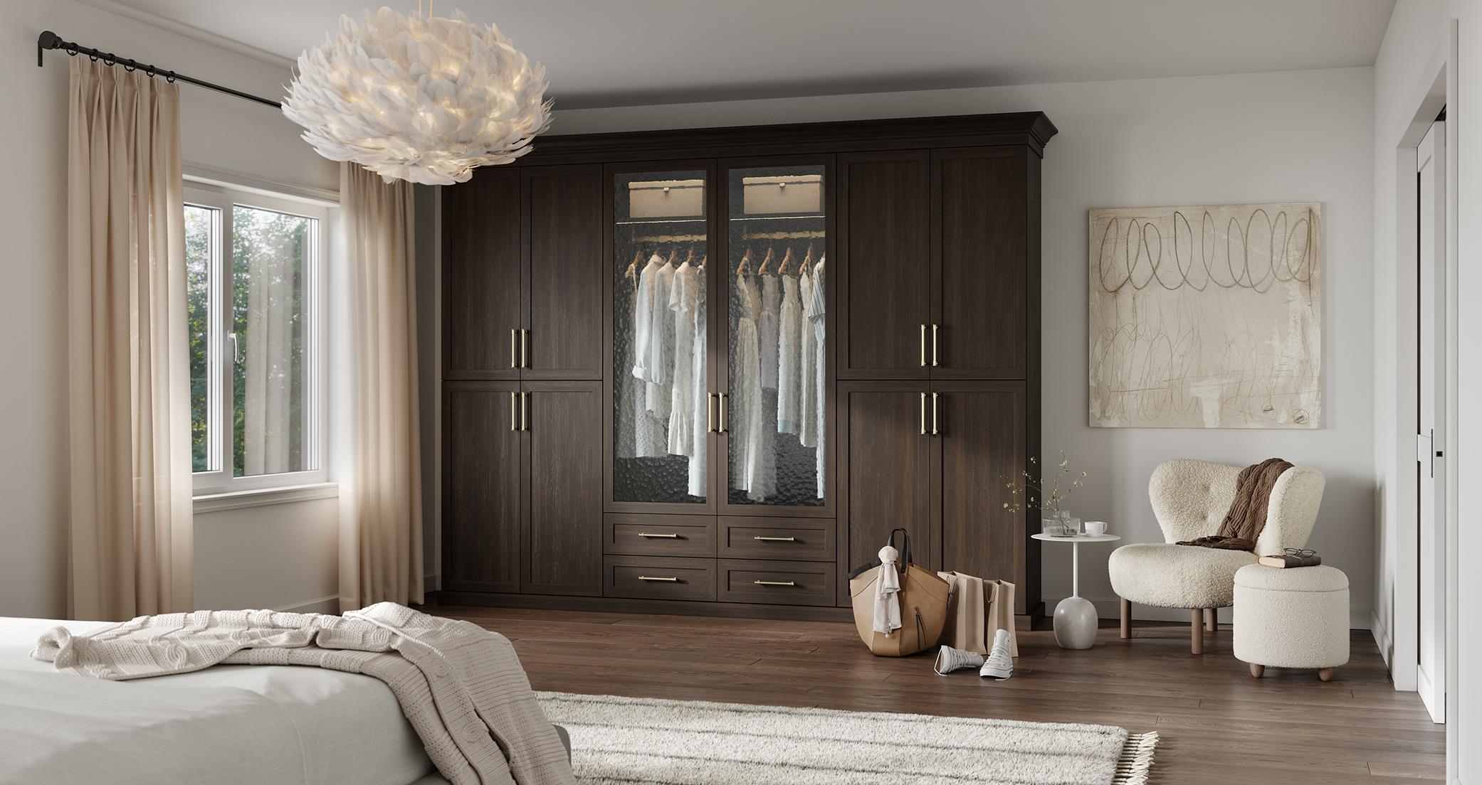Custom wardrobe closet design in dark wood grain finish with glass doors and metal hardware by California Closets