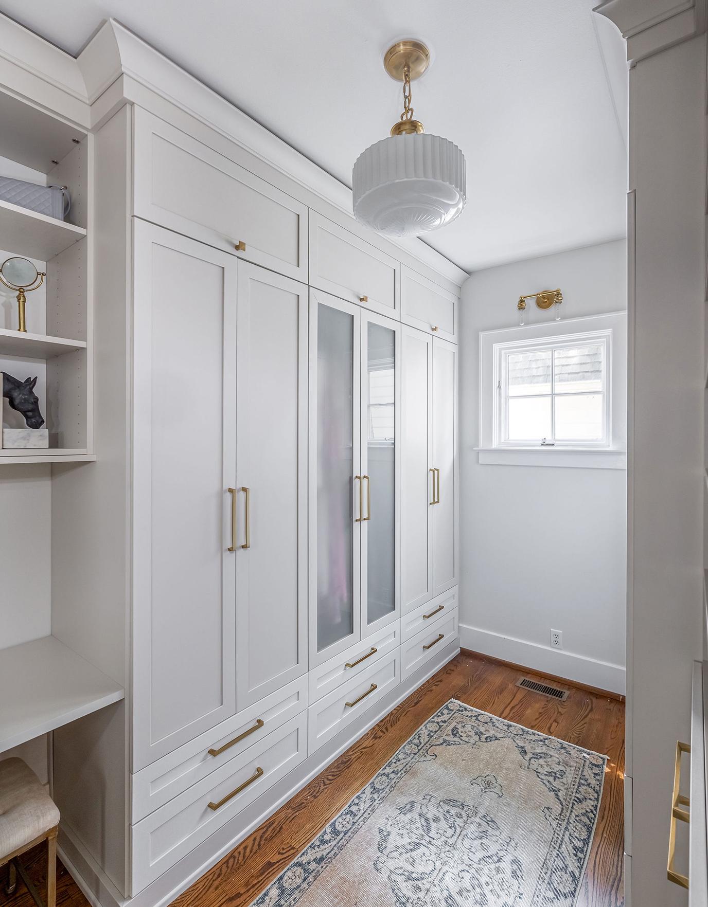 Pull out laundry cabinets in a walk in closet created for Candice King by California Closets