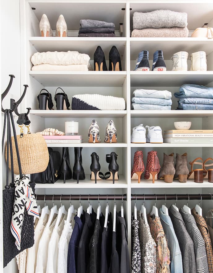 Organized eco-friendly capsule wardrobe in a white custom closet with open shoe shelving