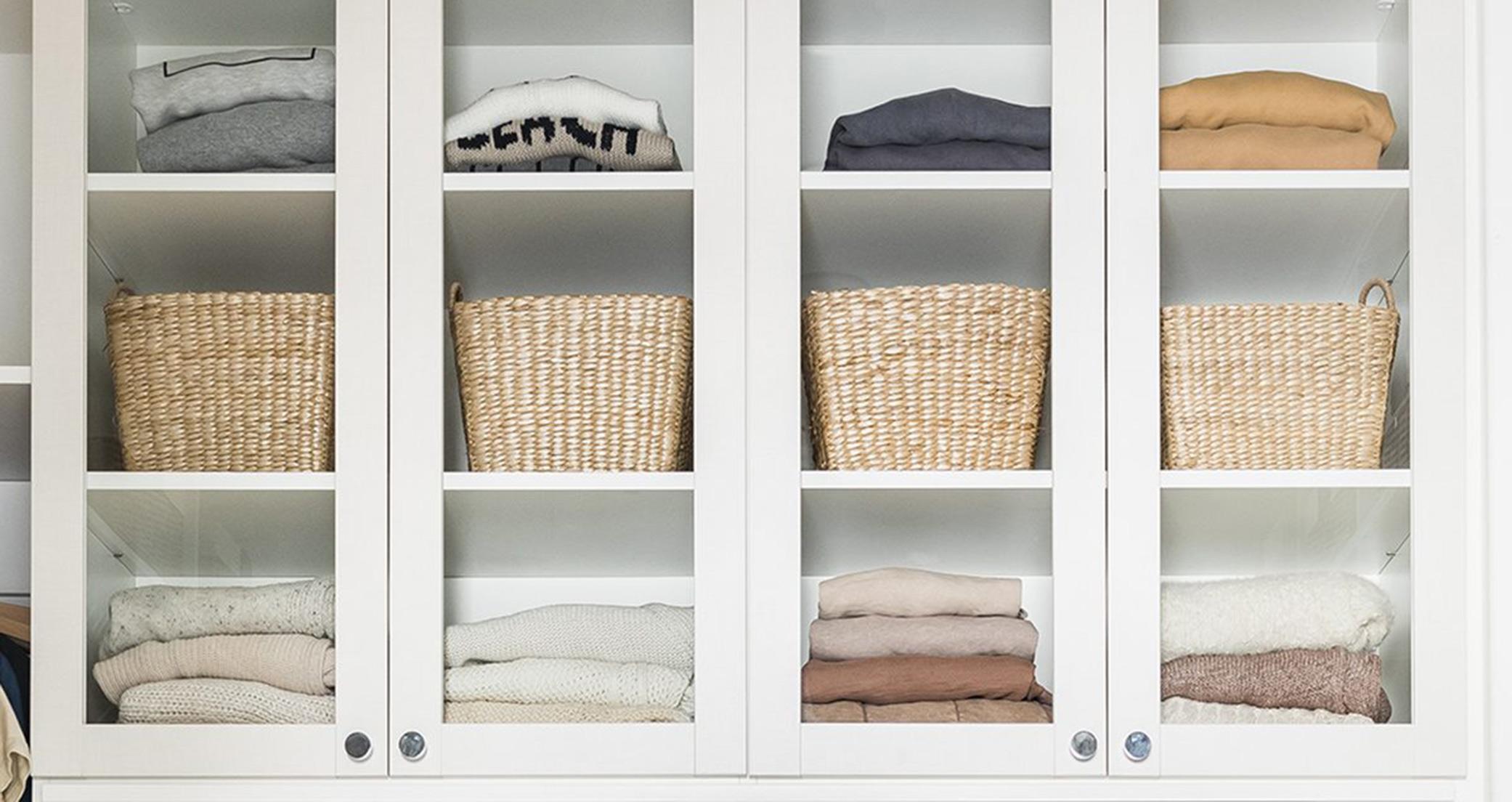 Las puertas de cristal del armario de ropa de cama del pasillo en acabado de madera veteada blanca de California Closets