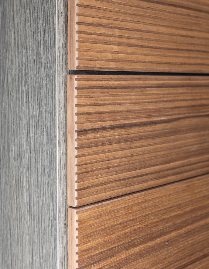 Close-up detail of custom closet drawers featuring a fluted warm wood texture and grey eco-friendly board finish