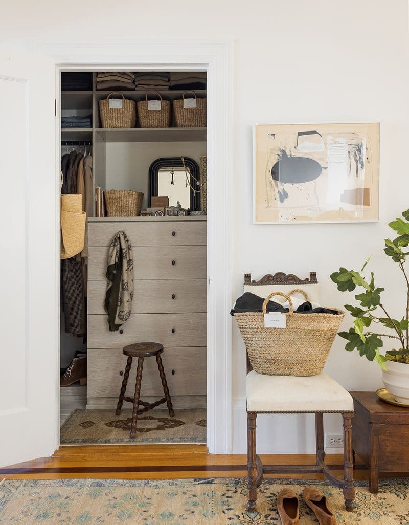 Un vistazo al vestidor con acabado de madera, estanterías y ropa colgada creado por California Closets.