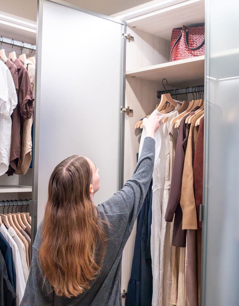 Armario guardarropa con gabinete colgante alto para vestidos largos en acabado de grano de madera con puertas de vidrio creado por California Closets
