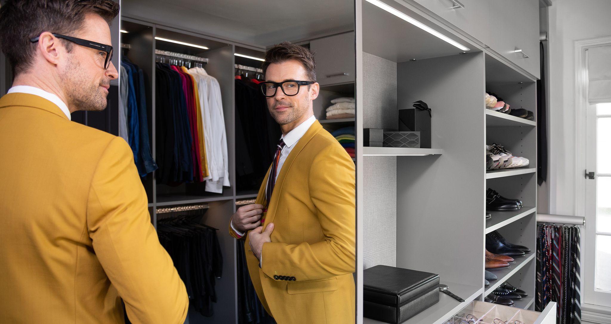 El presentador de moda Brad Goreski en su vestidor personalizado con cómoda incorporada de California Closets