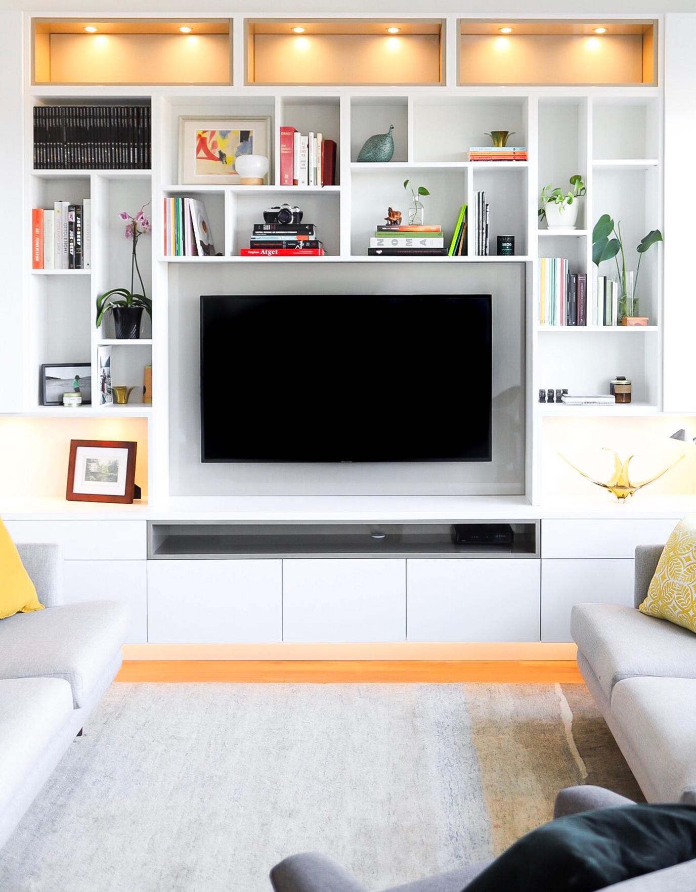 A custom built home entertainment center with shelving and cabinets in white wood finish by California Closets