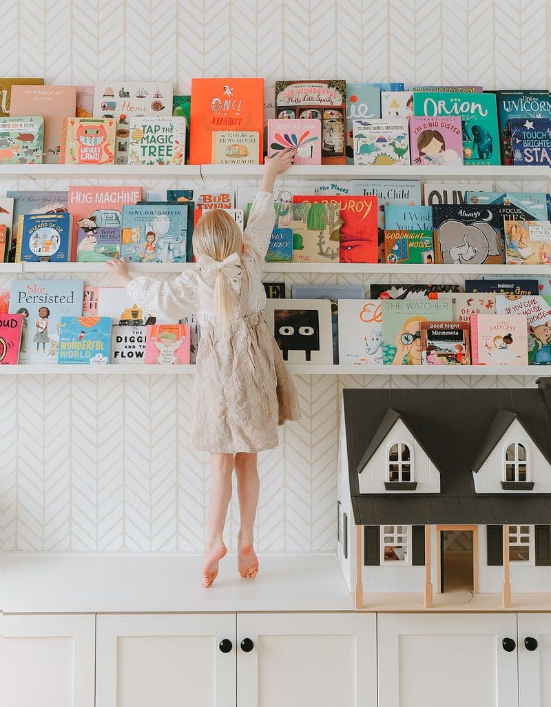 Child reaching for library bookshelves books designed in custom white finish by California Closets