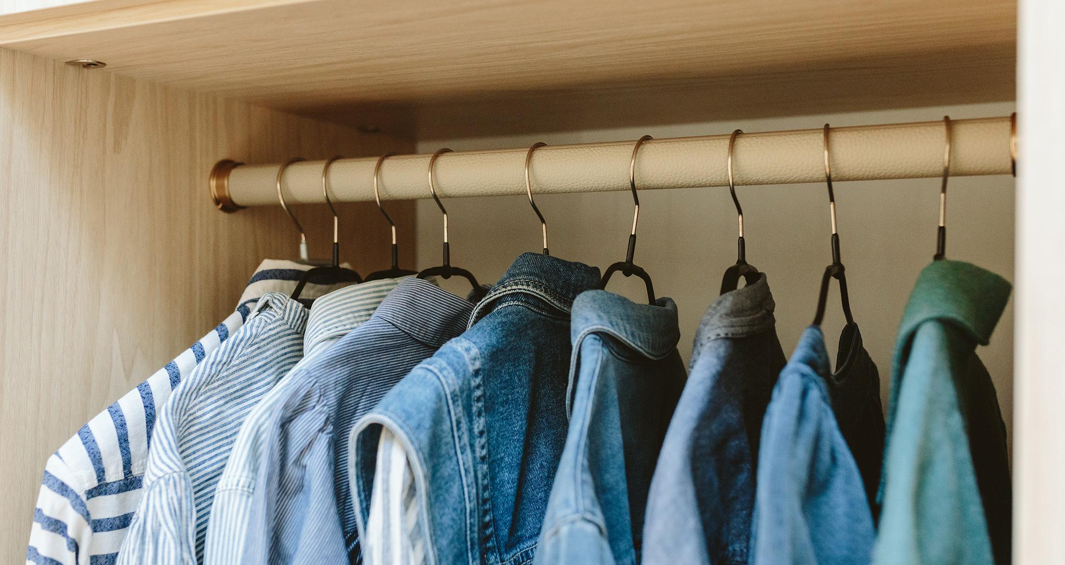 Close up of walk in closet custom wood grain finish clothes pole by California Closets