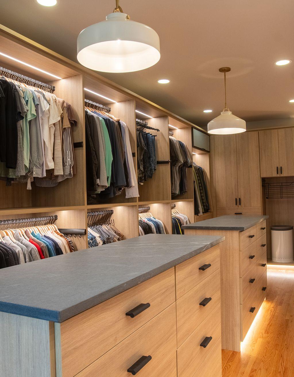 Diseño de vestidor con pasillo largo, islas centrales con iluminación LED y gabinetes personalizados con acabado en madera natural de California Closets