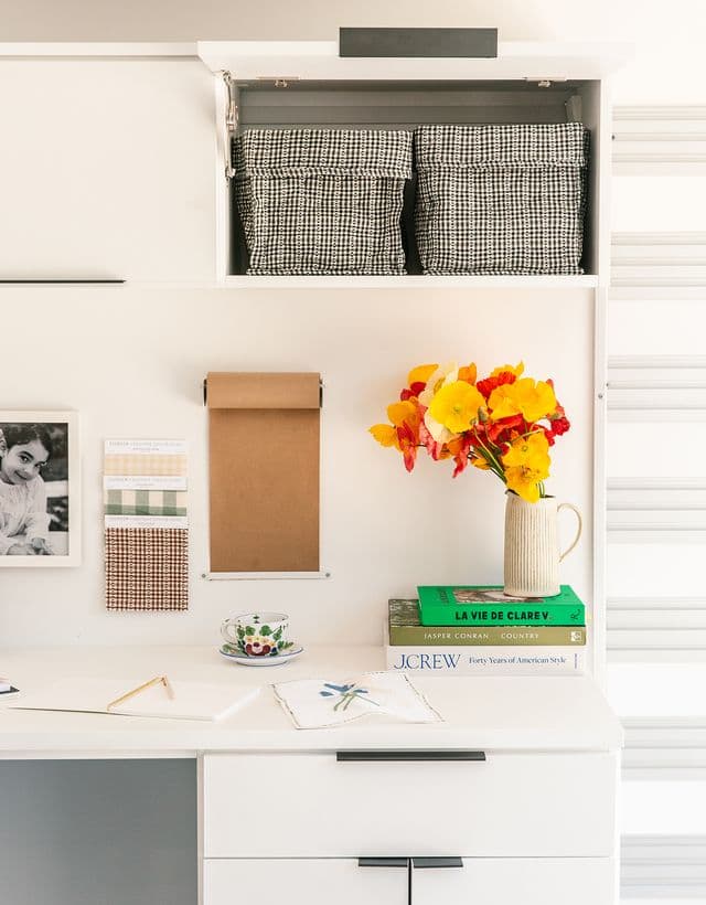Storage drawers and open cabinets in a built-in home office desk designed by California Closets