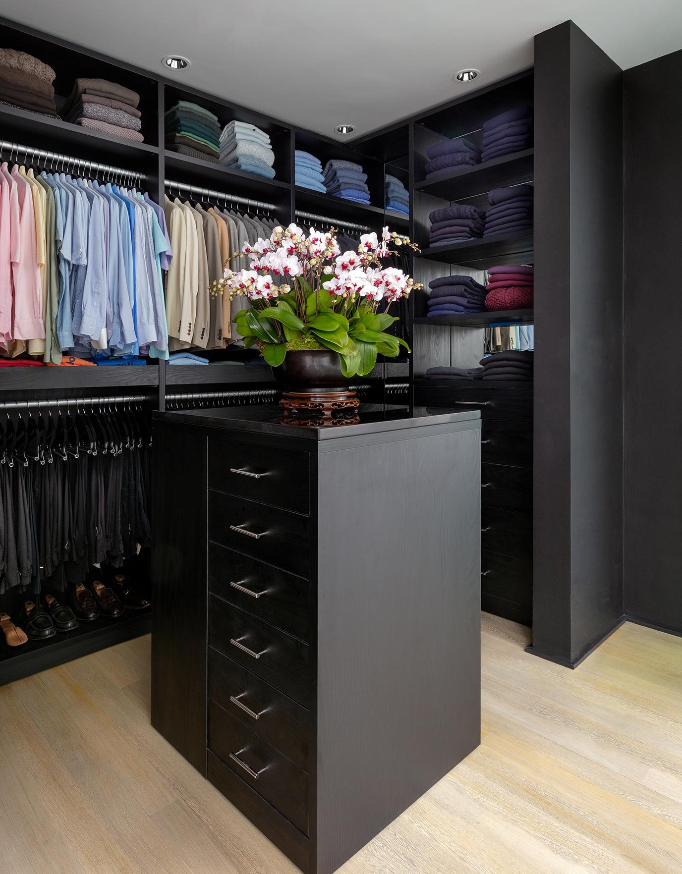 Center island storage in Kevin Sharkey's walk in closet designed in dark wood finish by California Closets