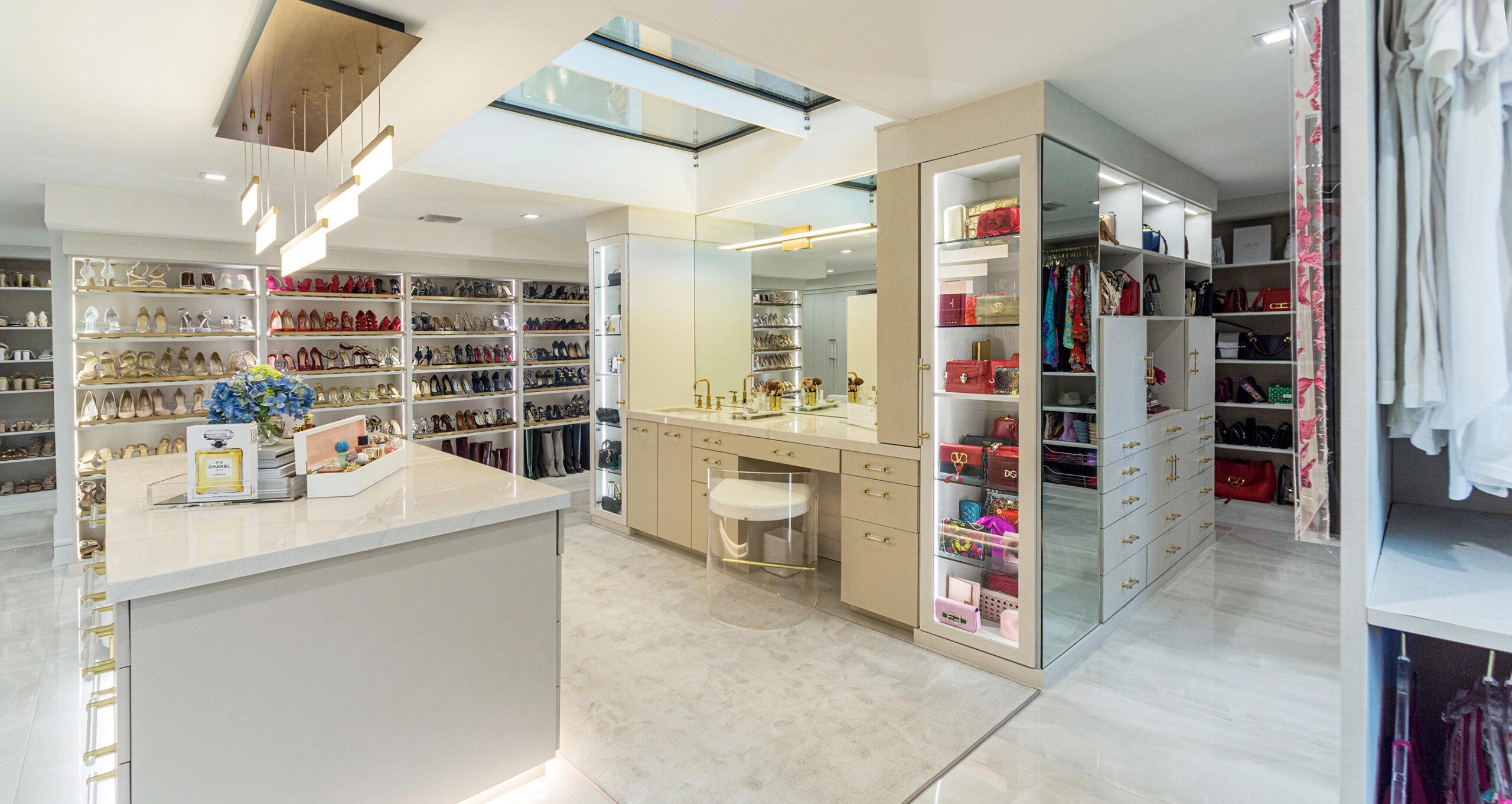 Walk in closet for a couple with extra wardrobe storage and center islands for accessories by California Closets