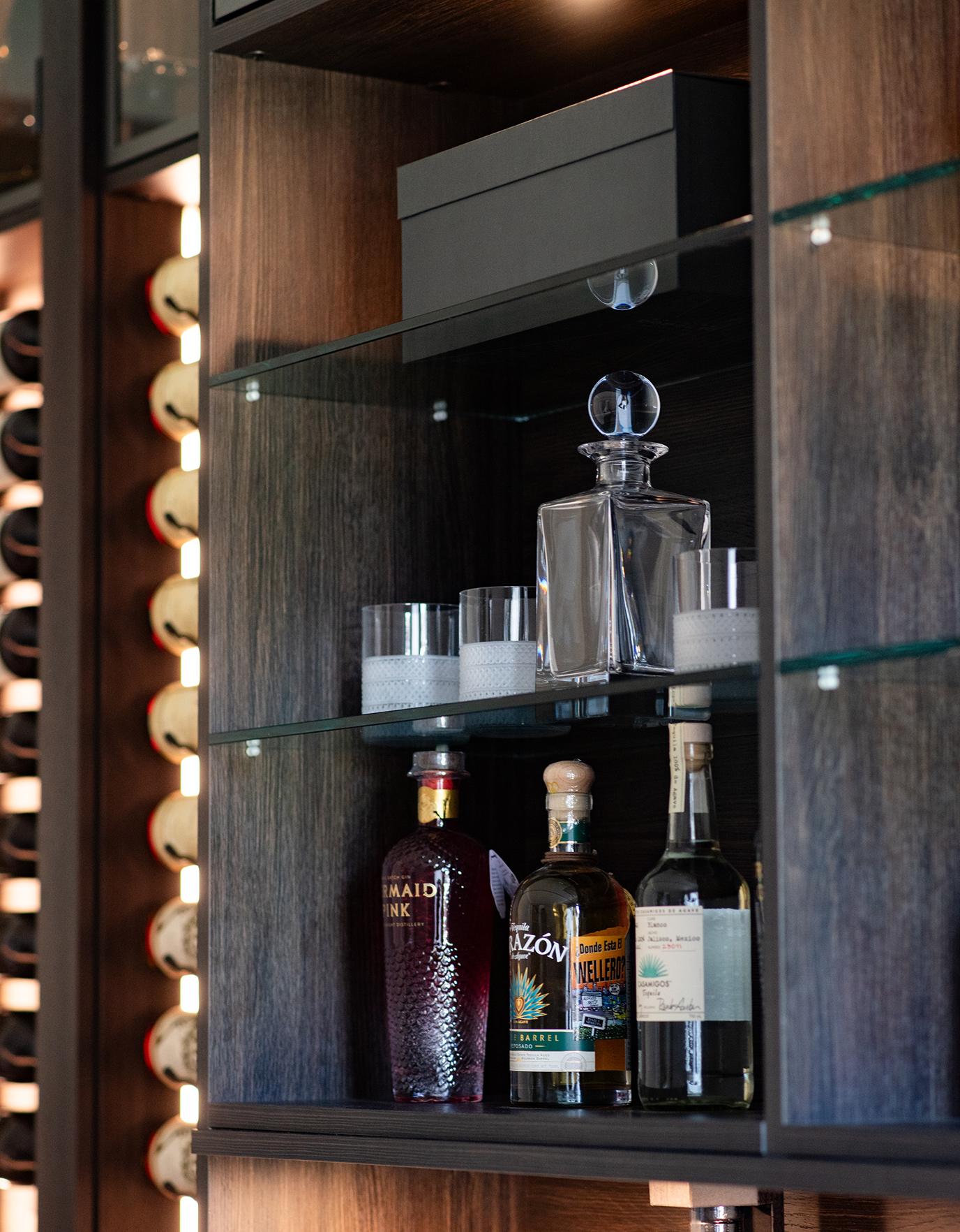 Detail of home wine bar shelving with LED lighting and vertical wine racks designed by California Closets