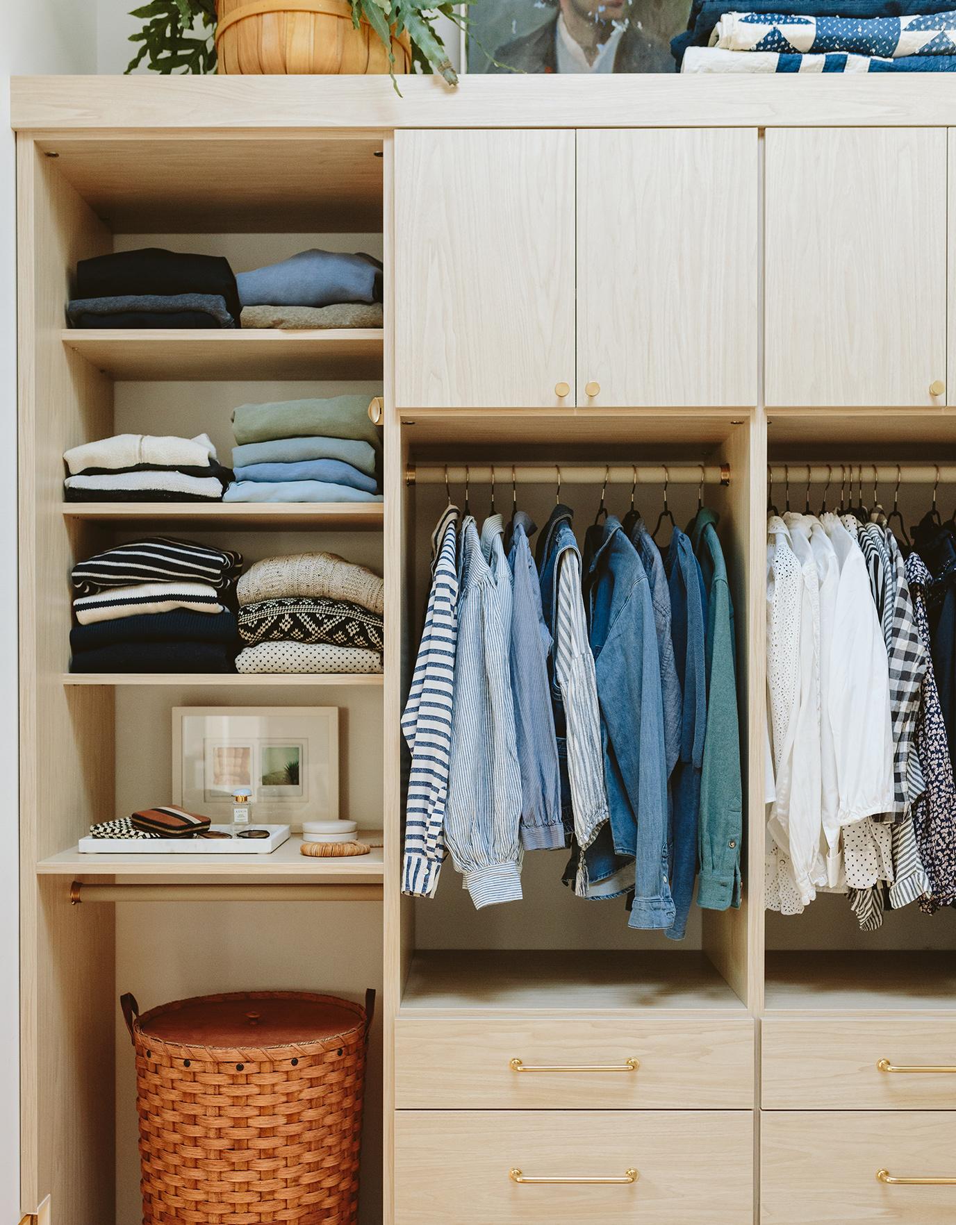 Built in cabinets and drawers in a walk in closet with open shelving in light wood grain finish by California Closets