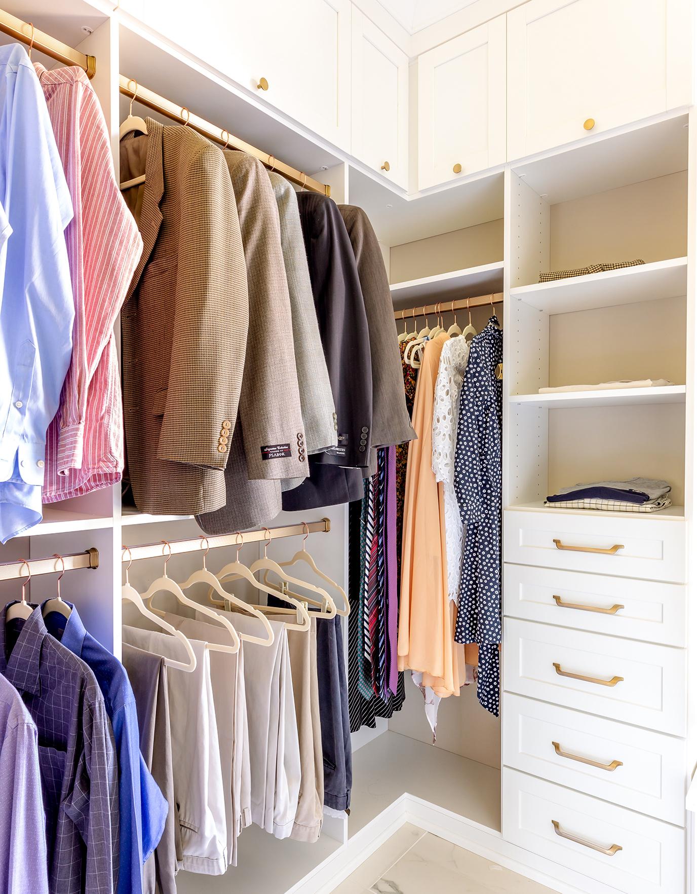 Walk in closet with corner wardrobe storage in white finish by California Closets