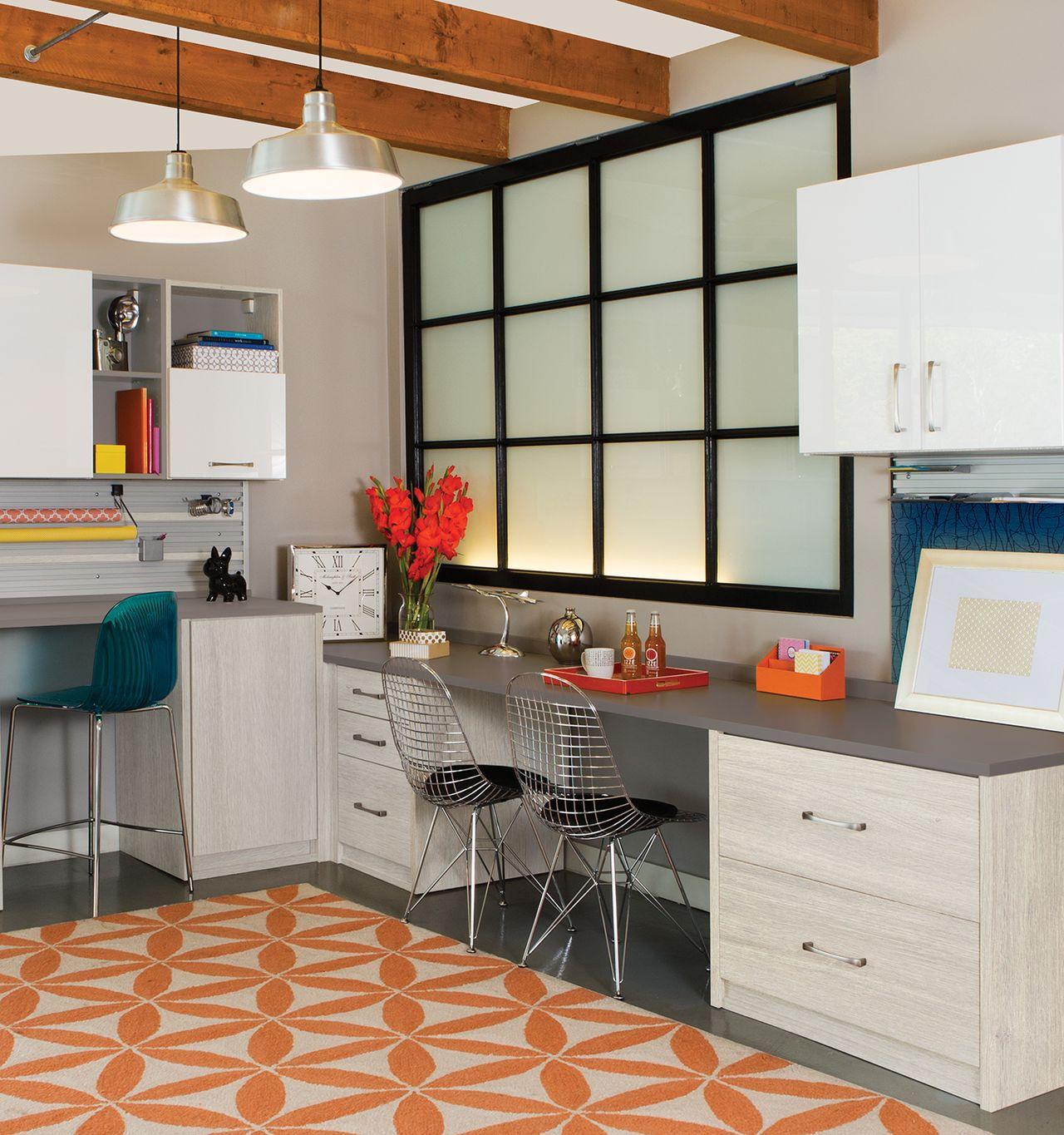 Sala de manualidades con estaciones de trabajo dobles y gabinetes de almacenamiento por California Closets