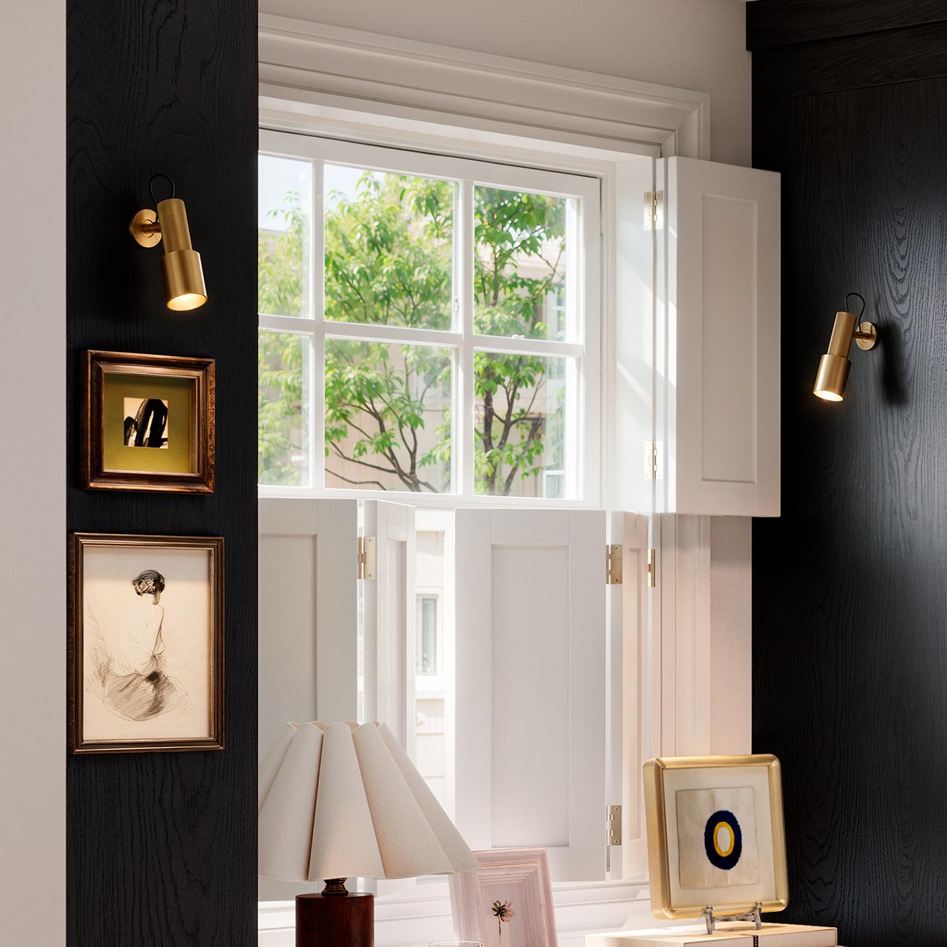 Handler picture light with a slim profile, featuring an adjustable cone‑shaped light and knurled texture, available in gold and gunmetal finishes.