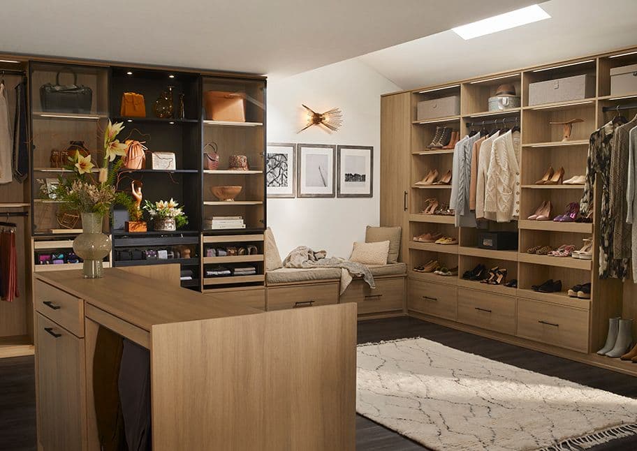 Vestidor configurado con isla central para joyería, con pared para zapatos, cajones personalizados y banco de California Closets