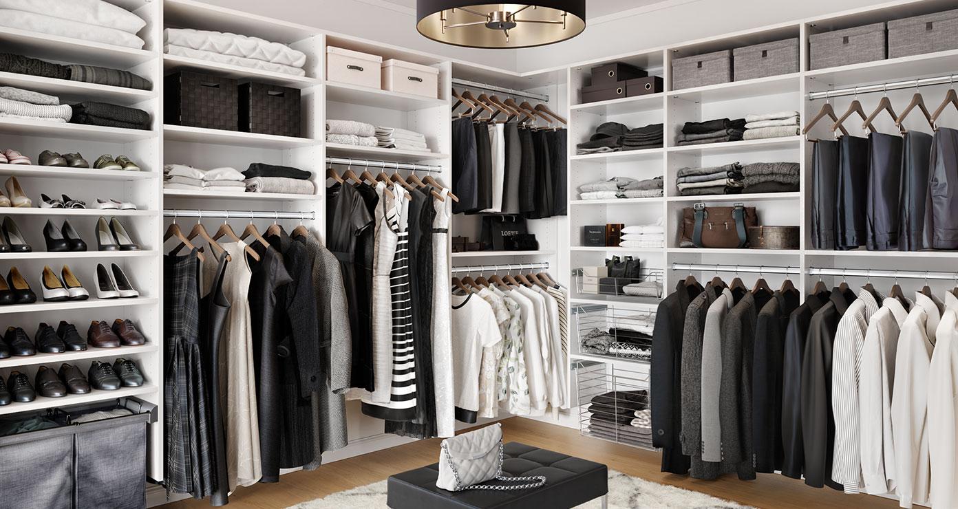 Walk in closet designed for his and hers wardrobe storage with center seating by California Closets