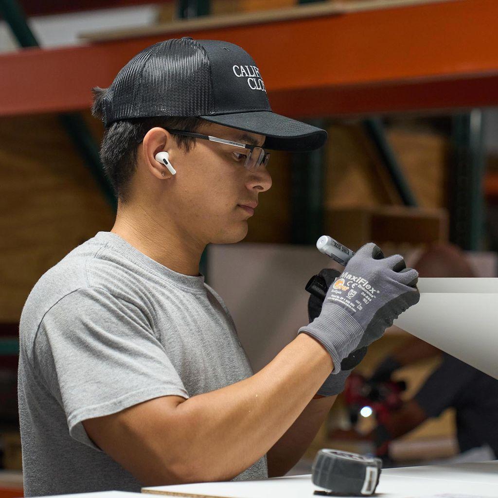 Aquí se muestra una planta de fabricación de materiales de California Closets que muestra la creación de un estante con acabado de vetas de madera