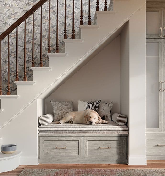 Diseño de almacenamiento en la entrada con banco debajo de las escaleras y gabinetes y cajones personalizados de California Closets