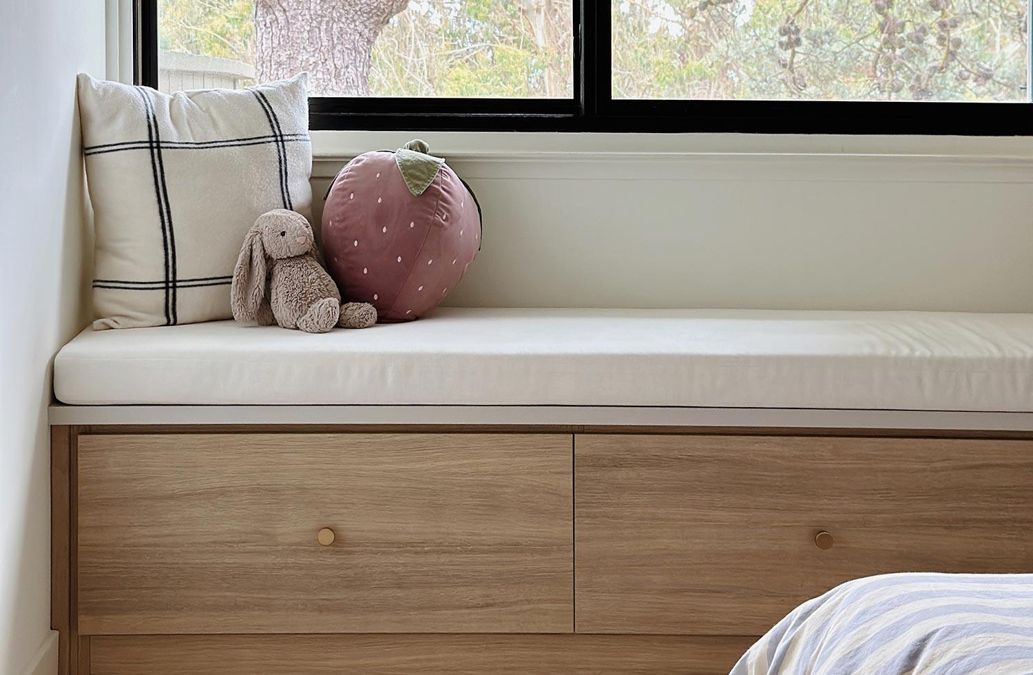 Banco con almacenamiento en acabado de madera clara debajo de la ventana de California Closets