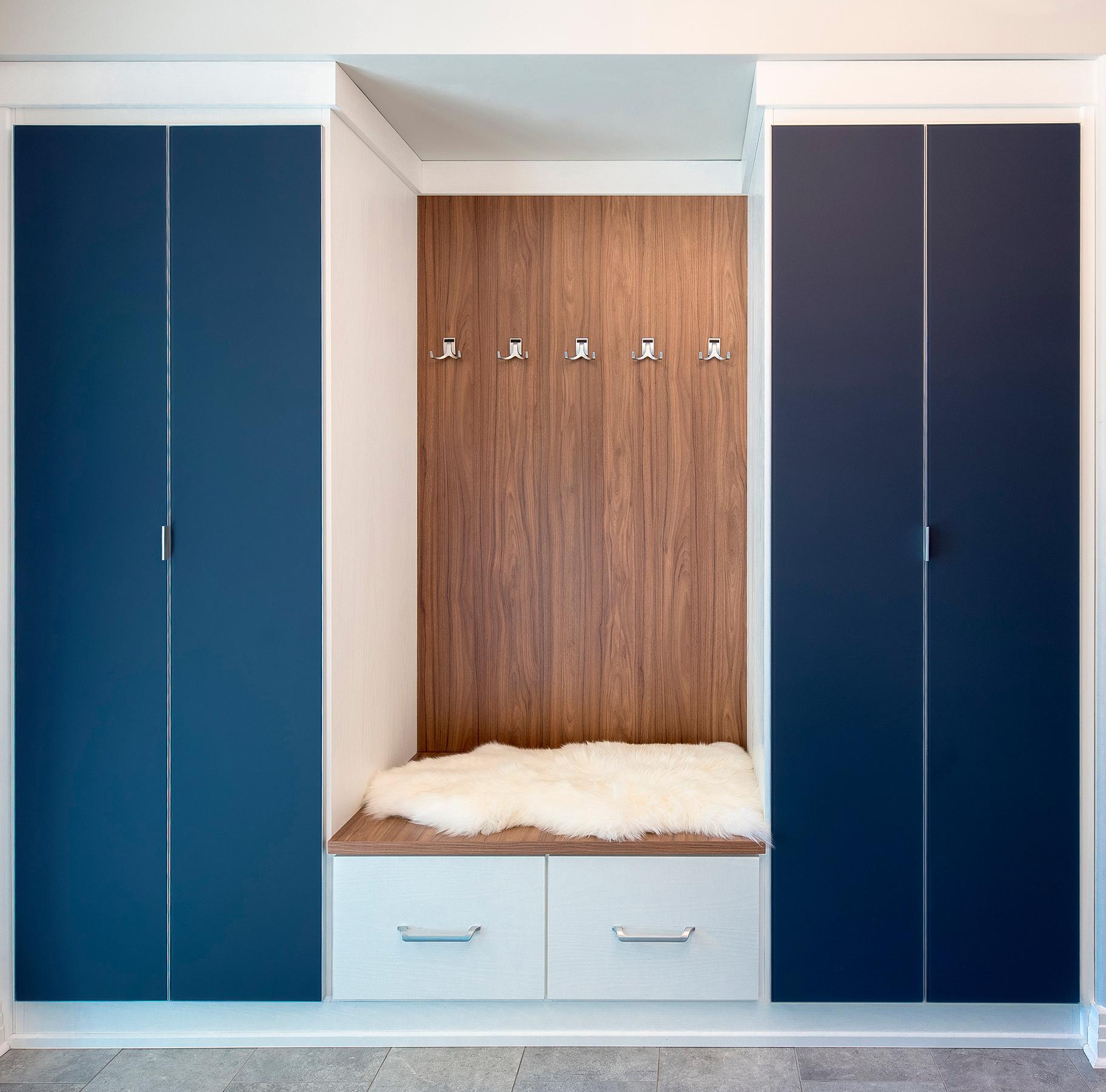 Custom entryway storage cabinets in blue wood finish with hooks for hanging coats, hats, and more by California Closets