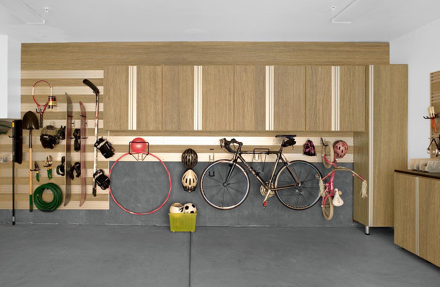Custom garage storage systems with wall track and cabinets by California Closets