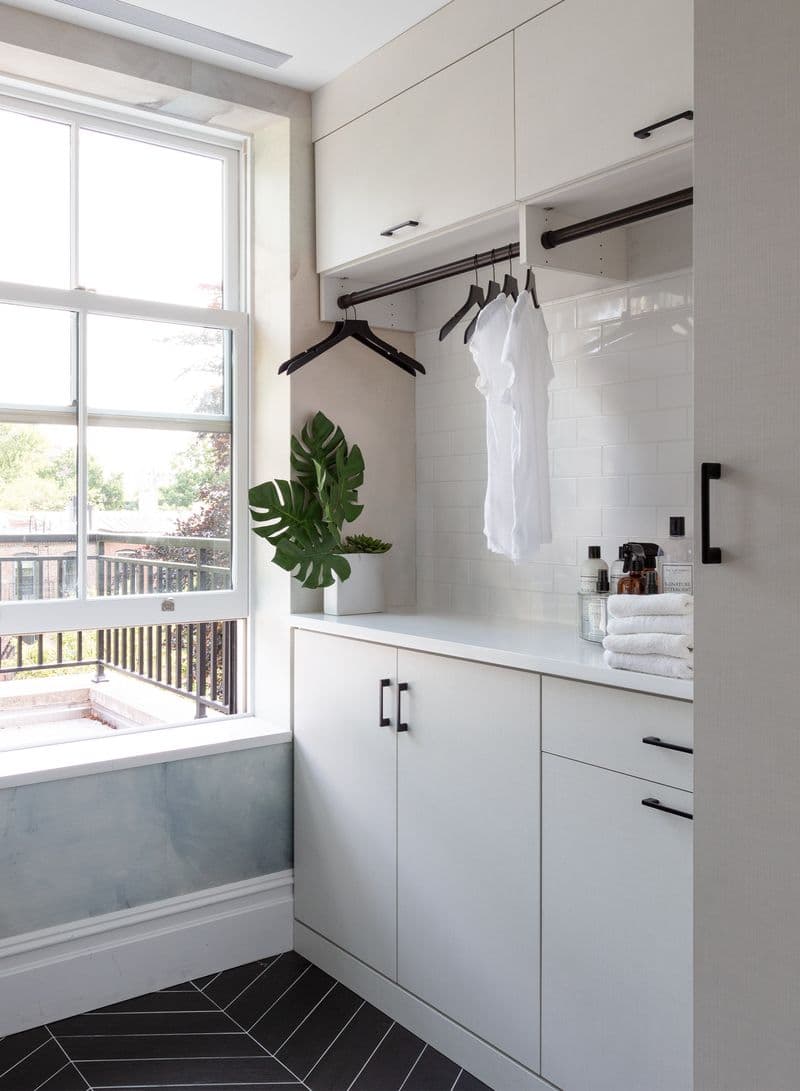 Cuarto de lavandería en casa tipo loft con gabinetes de almacenamiento personalizados y barras para colgar ropa para secado, creado por California Closets