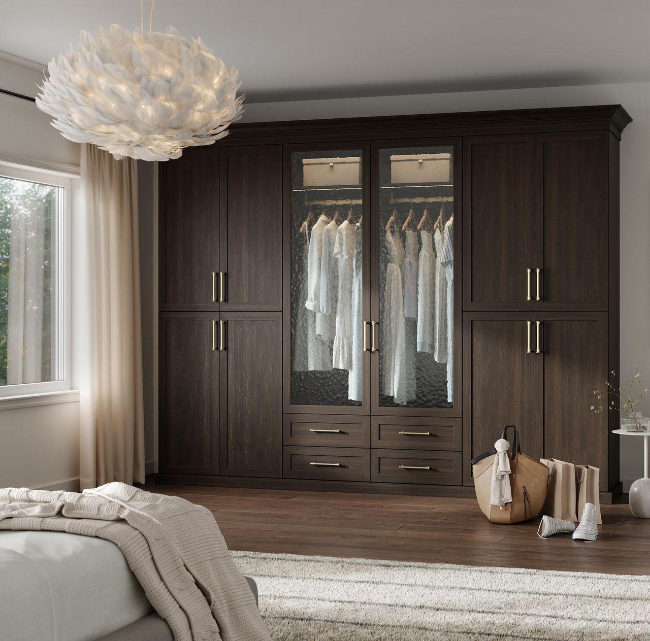 Diseno de armario empotrado a la pared con acabado de madera oscura por California Closets