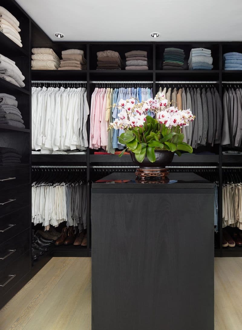 Dark wood finish design in walk in closet with center island by California Closets