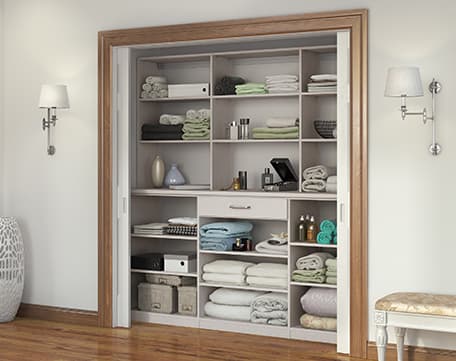 Armario para ropa blanca en el pasillo al alcance de la mano con estantes personalizados y cajón utilitario de California Closets