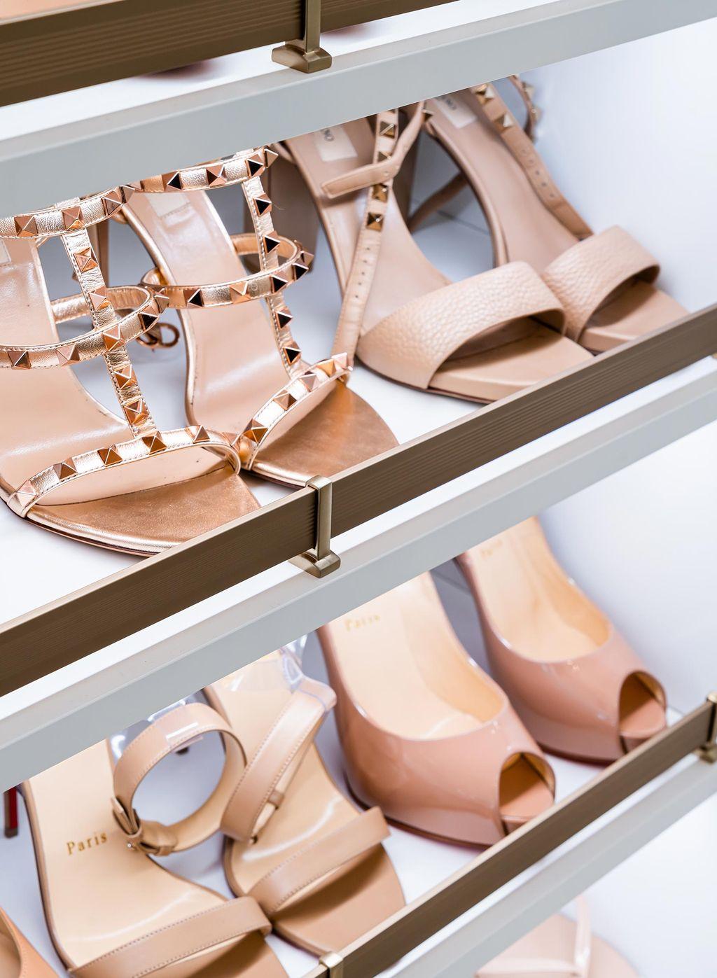 Shoe shelving with toe rails on slanted, lighted racks in closet by California Closets