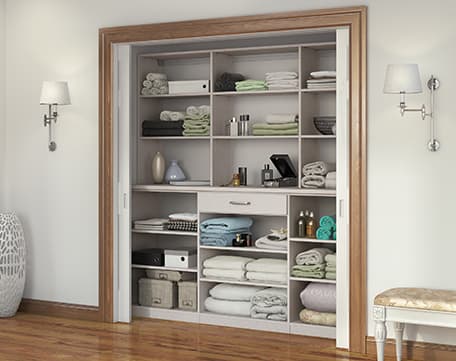 Hallway linens closet in reach in design with custom shelving and utility drawer by California Closets