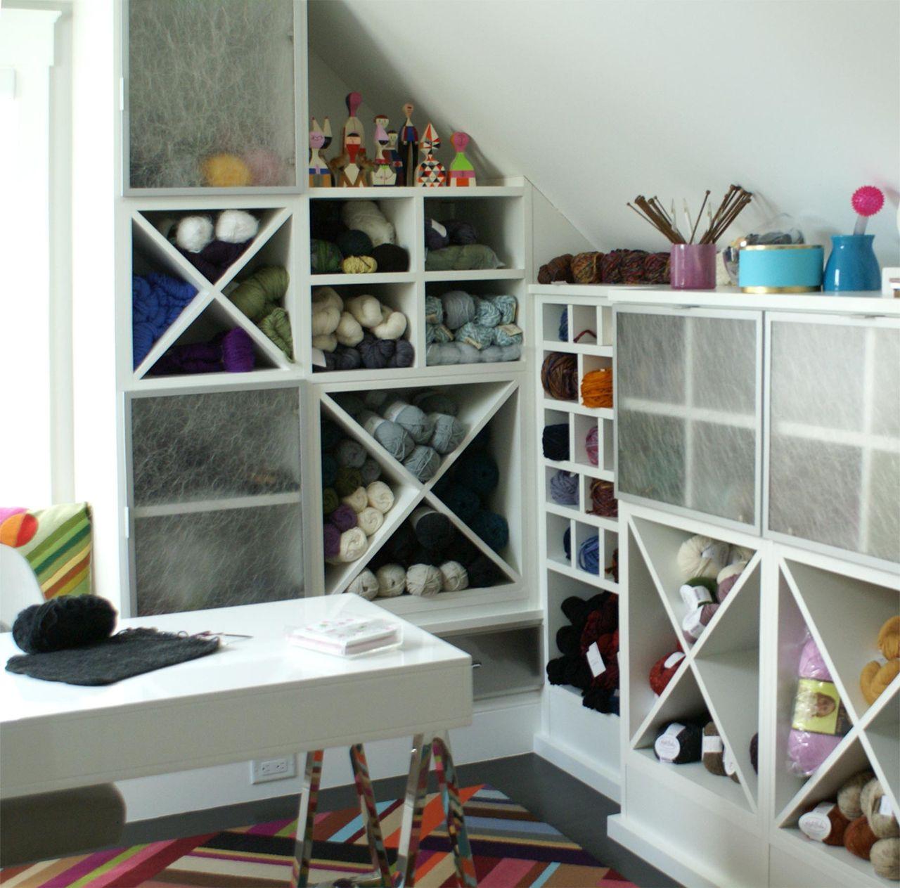 Estantería blanca en forma de X y cubos para guardar materiales con inserciones de ecoresina para ocultar el almacenamiento