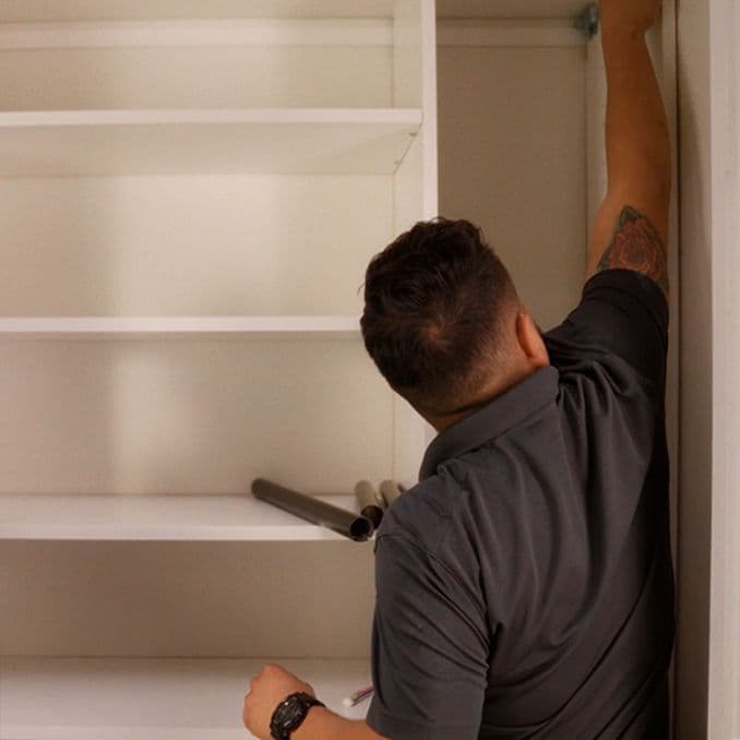 Técnico profesional de instalación en el lugar de trabajo, construyendo estanterías para armarios de California Closets.