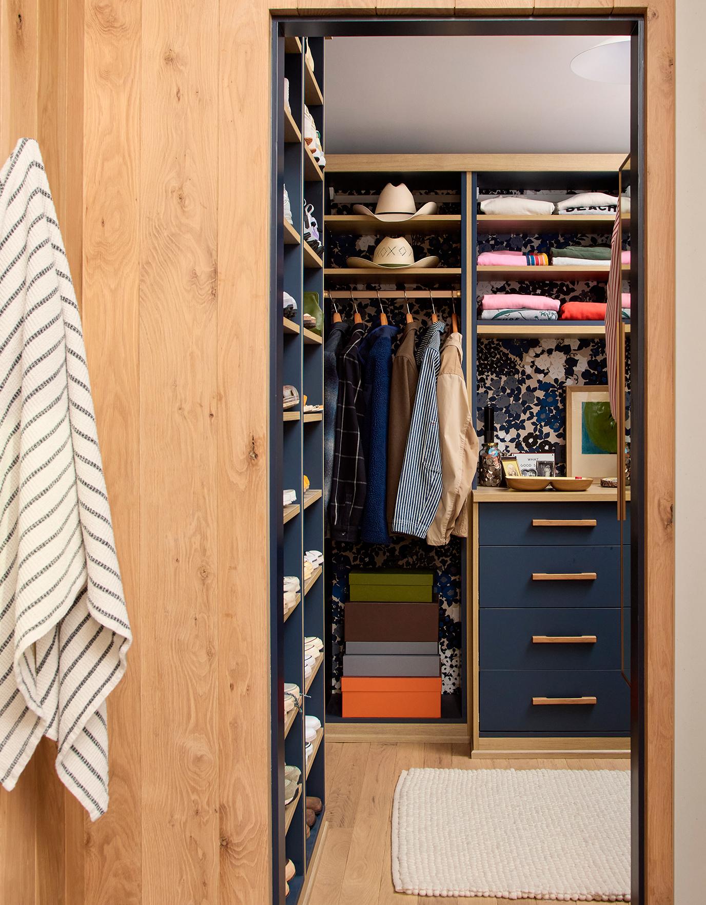A custom-designed walk-in closet by California Closets featuring tailored shelving, drawers, and hanging space with neatly stored clothing, hats, and boxes. | California Closets