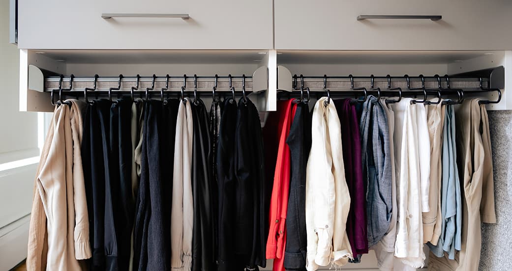 Wardrobe closet clothing rods shown under floating cabinets from California Closets