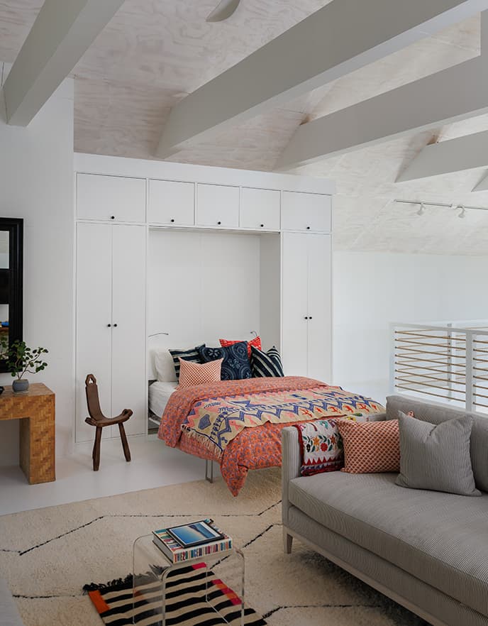 An opened Murphy wall bed show with white wood framing and storage cabinets from California Closets