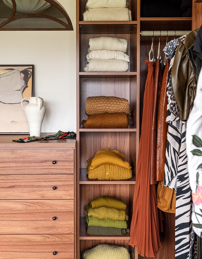 Vista cercana de estanterías abiertas de piso a techo para almacenamiento de suéteres en un vestidor de California Closets