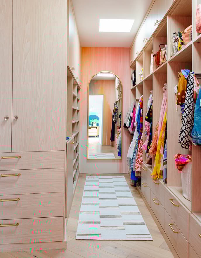 Clóset vestidor largo y estrecho con cubos y repisas personalizados en un lado y espacio para colgar ropa en el otro, de California Closets.