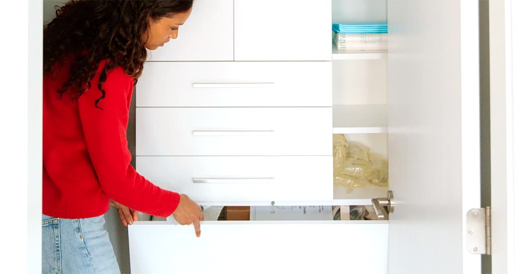 Mom in kids closets with custom cabinets and drawer in white finish from California Closets