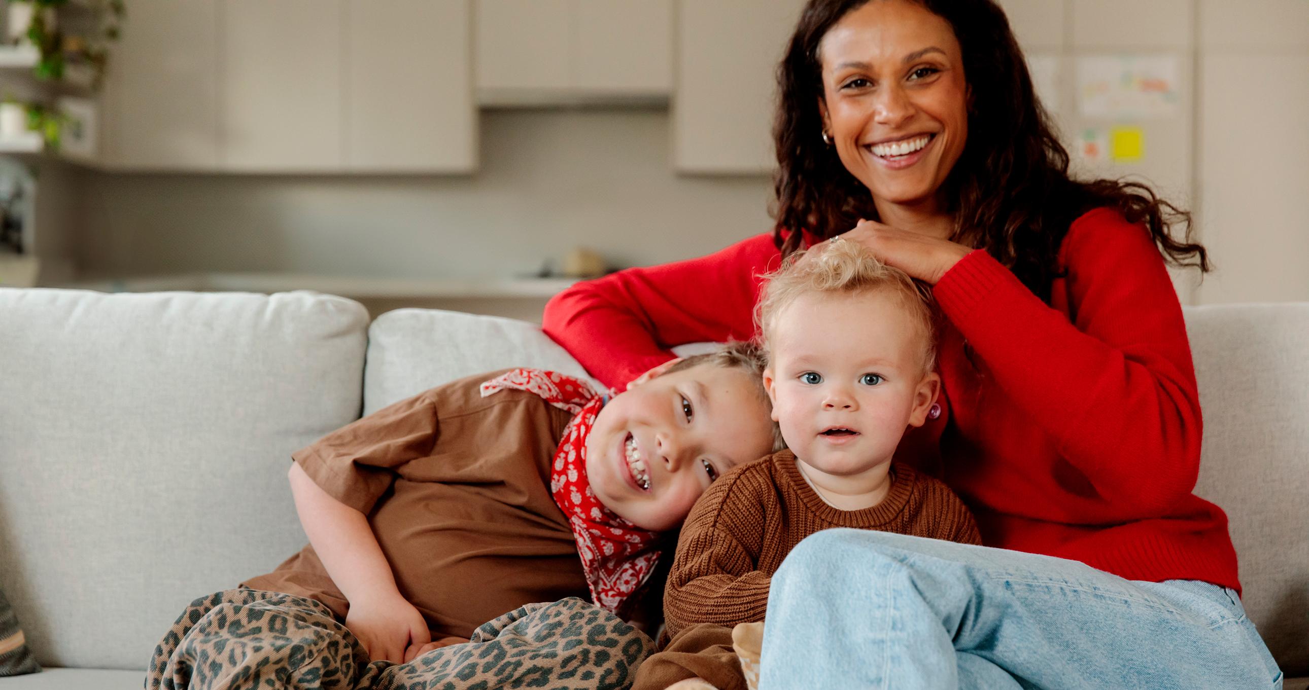 Model Alex Bonnesen sitting on sofa with kids in front of custom storage cabinets from California Closets