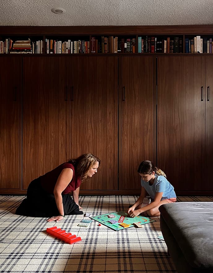 Sala multipropósito con camas abatibles ocultas y familia jugando en un espacio personalizado de California Closets