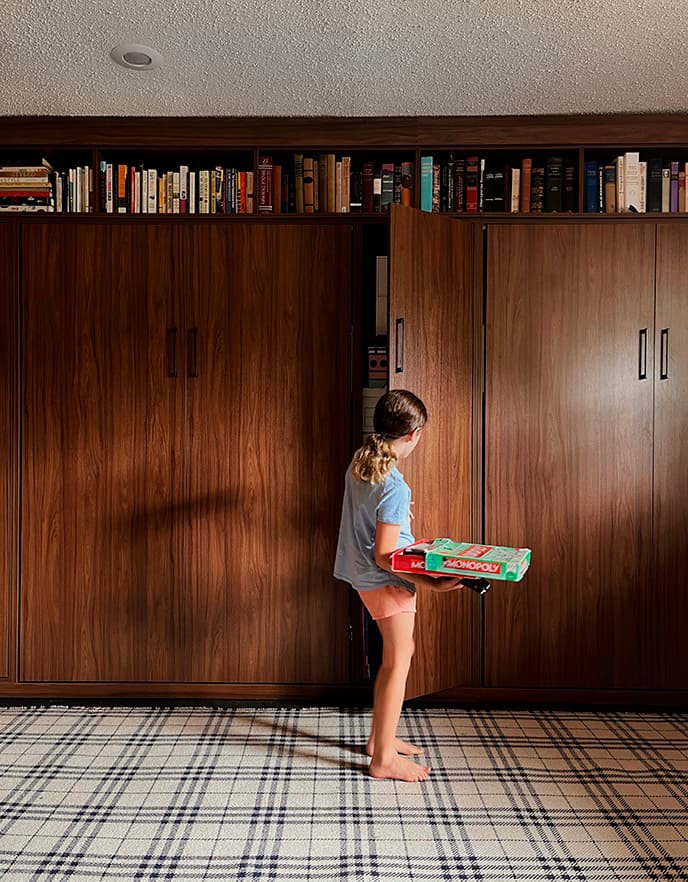 Game room and guest room with hidden wall beds and storage in dark wood finish from California Closets