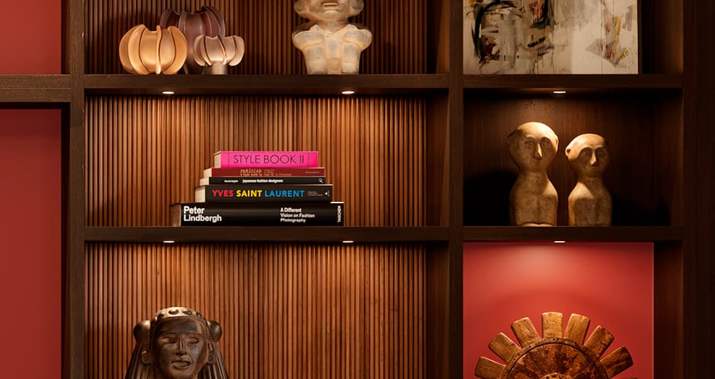 Close-up of bookcase with fluted wood backing, warm lighting, and curated decor by California Closets.